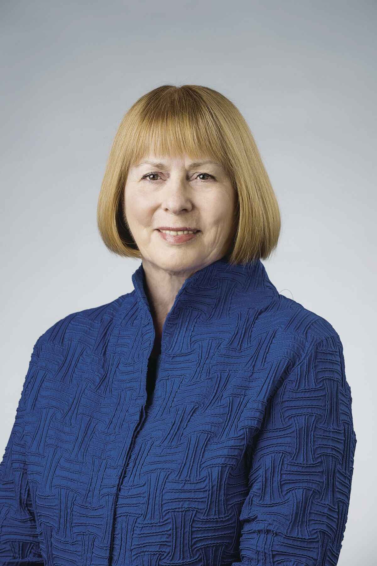 a woman looks at the camera in a patterened blue blazer