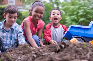 three children playing in dirt pit